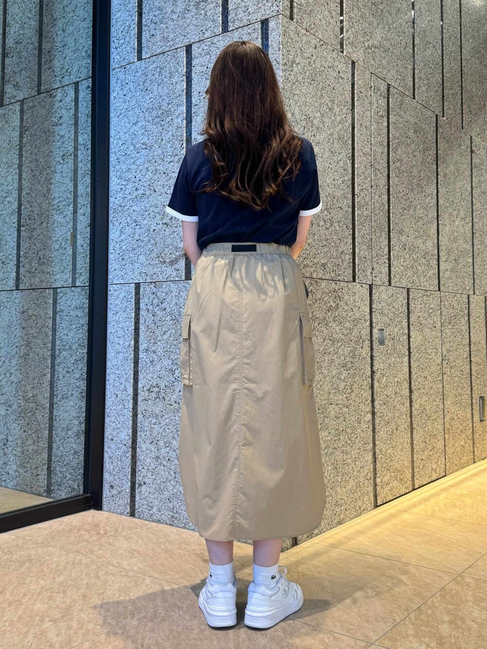 ブルー系のTシャツ/カットソー、ベージュ系のスカート、ホワイト系のスニーカーを着用したレディースの春コーディネートの3枚目の写真