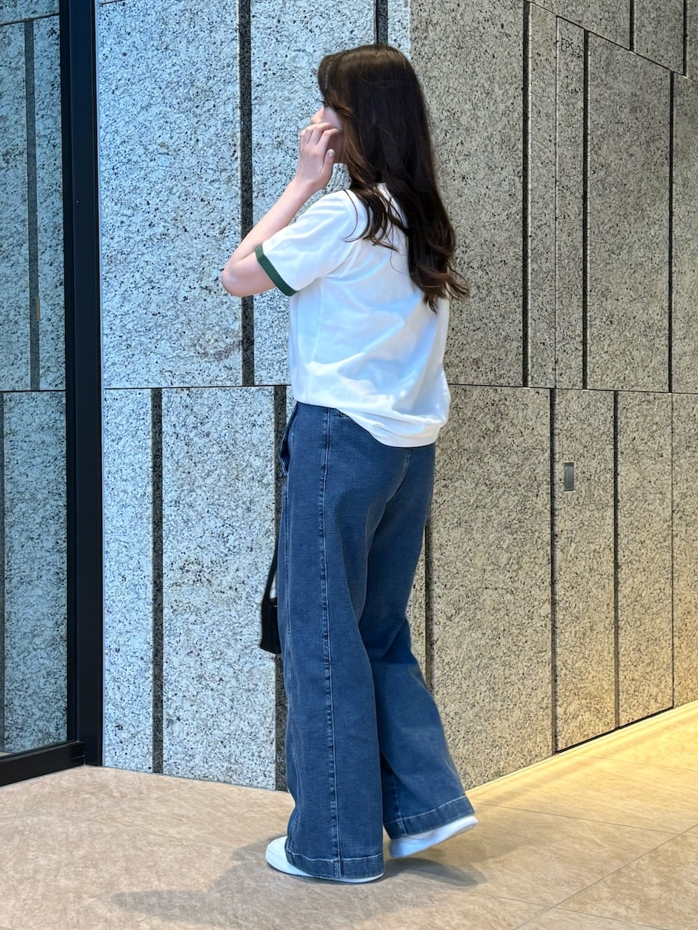 グリーン系のTシャツ/カットソー、ブラック系のバッグ、ブルー系のデニムパンツを着用したレディースの春コーディネートの3枚目の写真