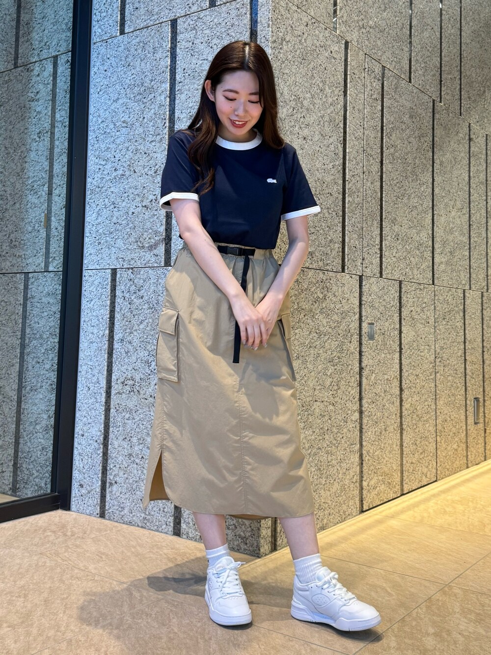 ブルー系のTシャツ/カットソー、ベージュ系のスカート、ホワイト系のスニーカーを着用したレディースの春コーディネートの2枚目の写真