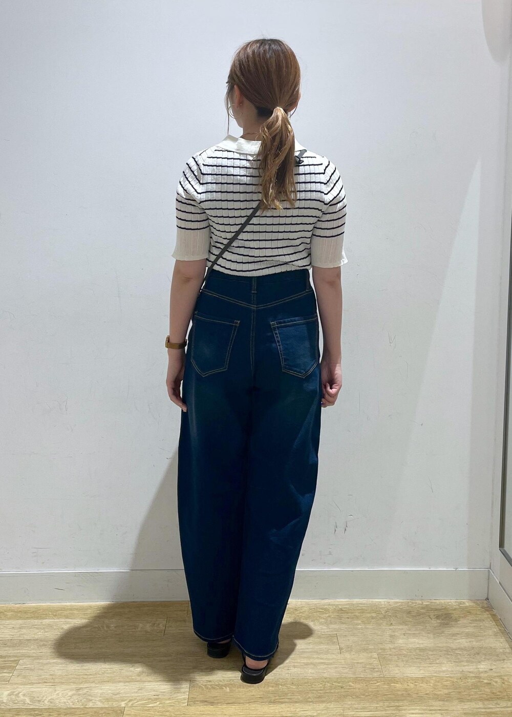 ホワイト系のニット/セーター、ブルー系のデニムパンツ、グレー系のショルダーバッグを着用したレディースの夏コーディネートの3枚目の写真