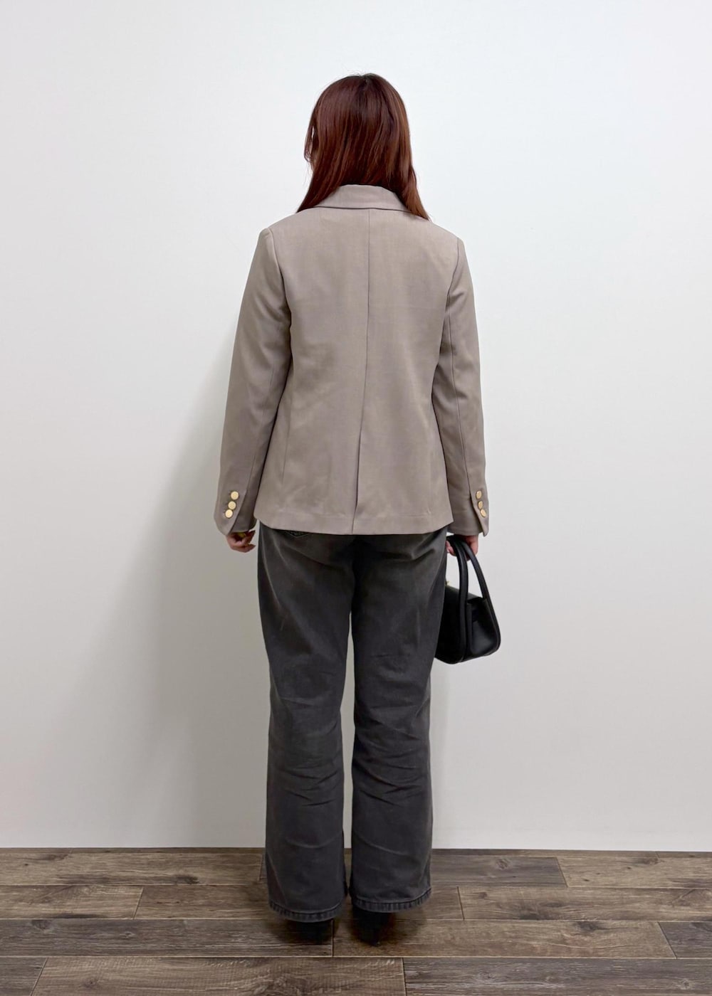 ブラック系のデニムパンツ、ブラック系のショルダーバッグ、ブラウン系のニット/セーターを着用したレディースの冬コーディネートの3枚目の写真