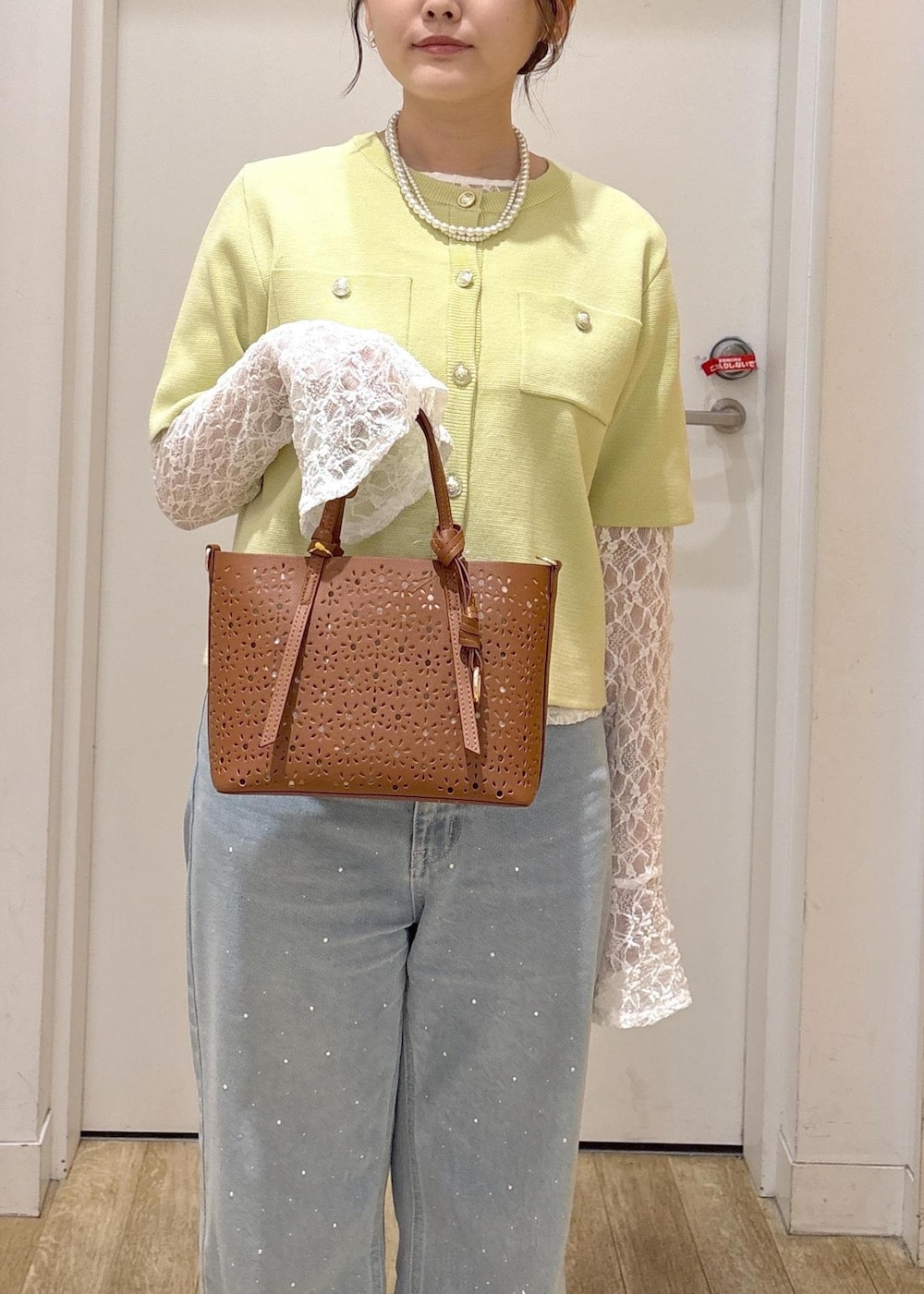 ブルー系のデニムパンツ、ブラウン系のショルダーバッグ、グリーン系のカーディガン/ボレロを着用したレディースの春コーディネートの7枚目の写真