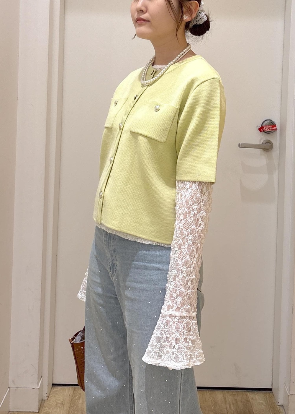 ブルー系のデニムパンツ、ブラウン系のショルダーバッグ、グリーン系のカーディガン/ボレロを着用したレディースの春コーディネートの6枚目の写真