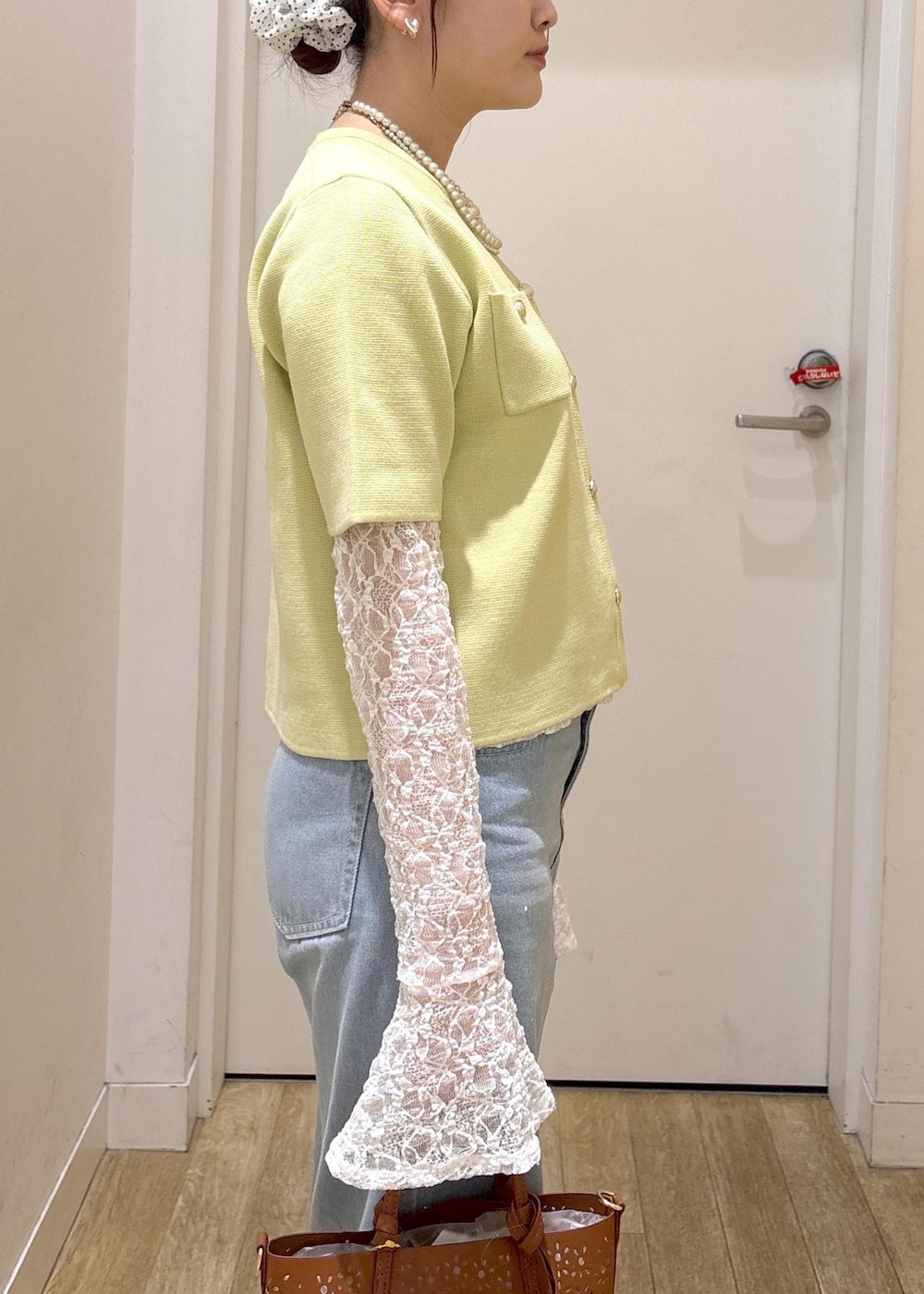 ブルー系のデニムパンツ、ブラウン系のショルダーバッグ、グリーン系のカーディガン/ボレロを着用したレディースの春コーディネートの5枚目の写真