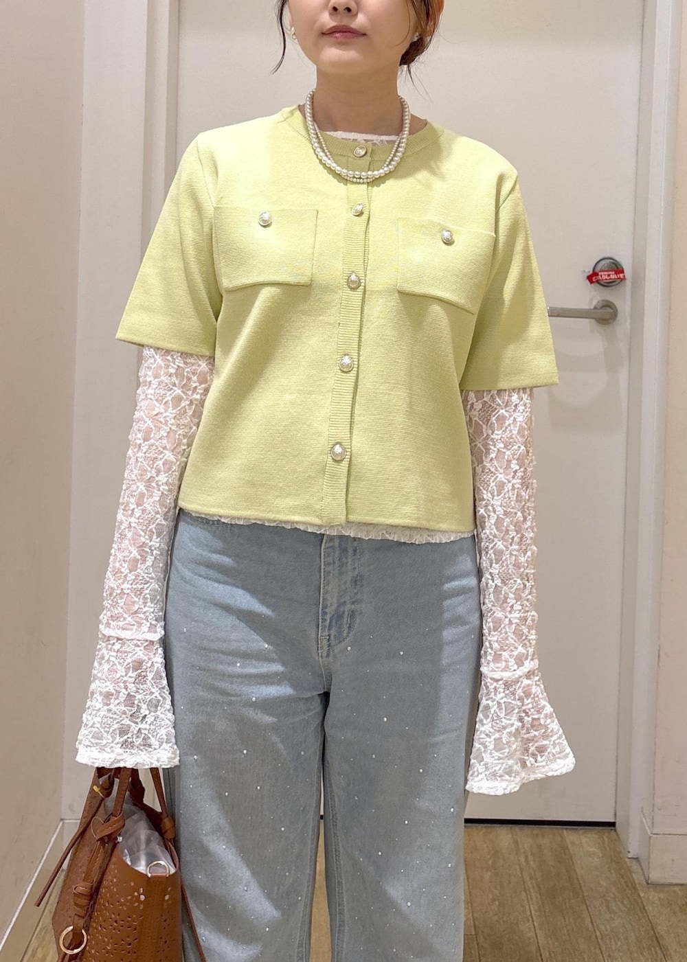 ブルー系のデニムパンツ、ブラウン系のショルダーバッグ、グリーン系のカーディガン/ボレロを着用したレディースの春コーディネートの4枚目の写真