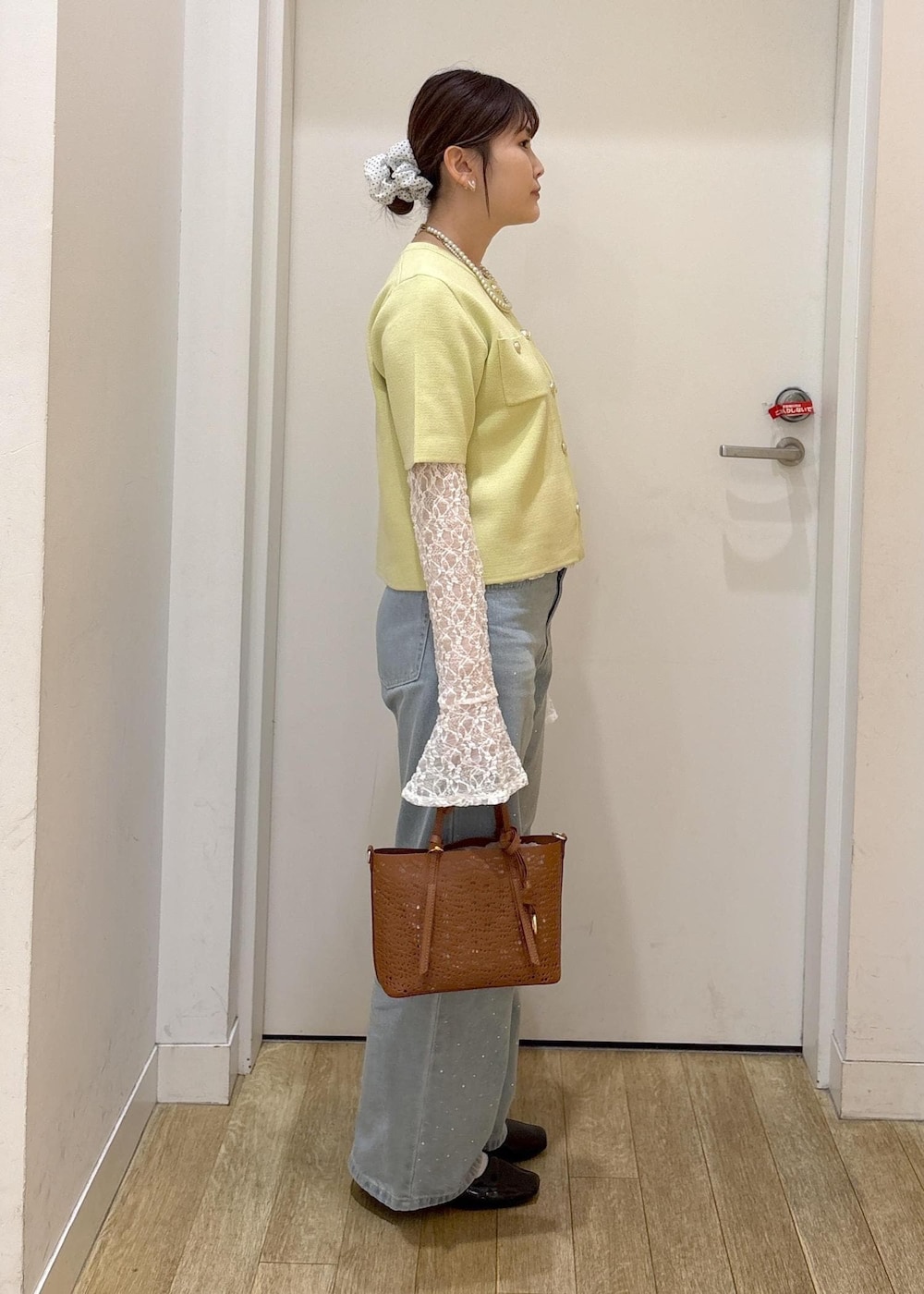 ブルー系のデニムパンツ、ブラウン系のショルダーバッグ、グリーン系のカーディガン/ボレロを着用したレディースの春コーディネートの2枚目の写真