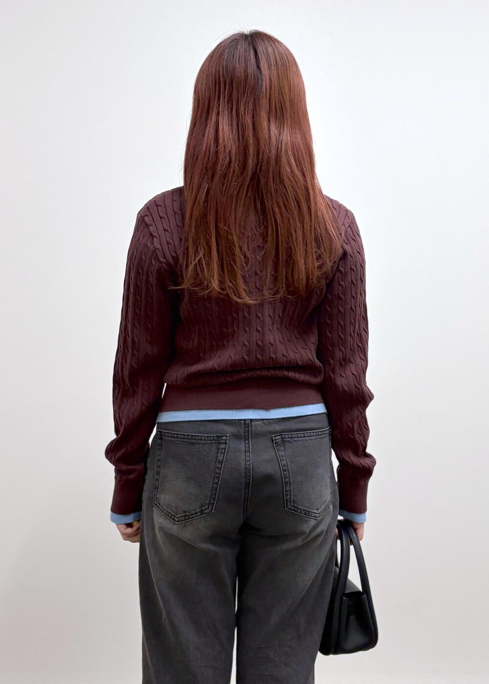 ブラック系のデニムパンツ、ブラック系のショルダーバッグ、ブラウン系のニット/セーターを着用したレディースの冬コーディネートの6枚目の写真