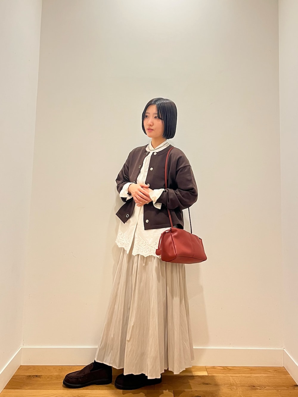 ホワイト系のシャツ/ブラウス、ブラウン系のカーディガン/ボレロ、ホワイト系のスカートを着用したレディースの秋コーディネートの2枚目の写真