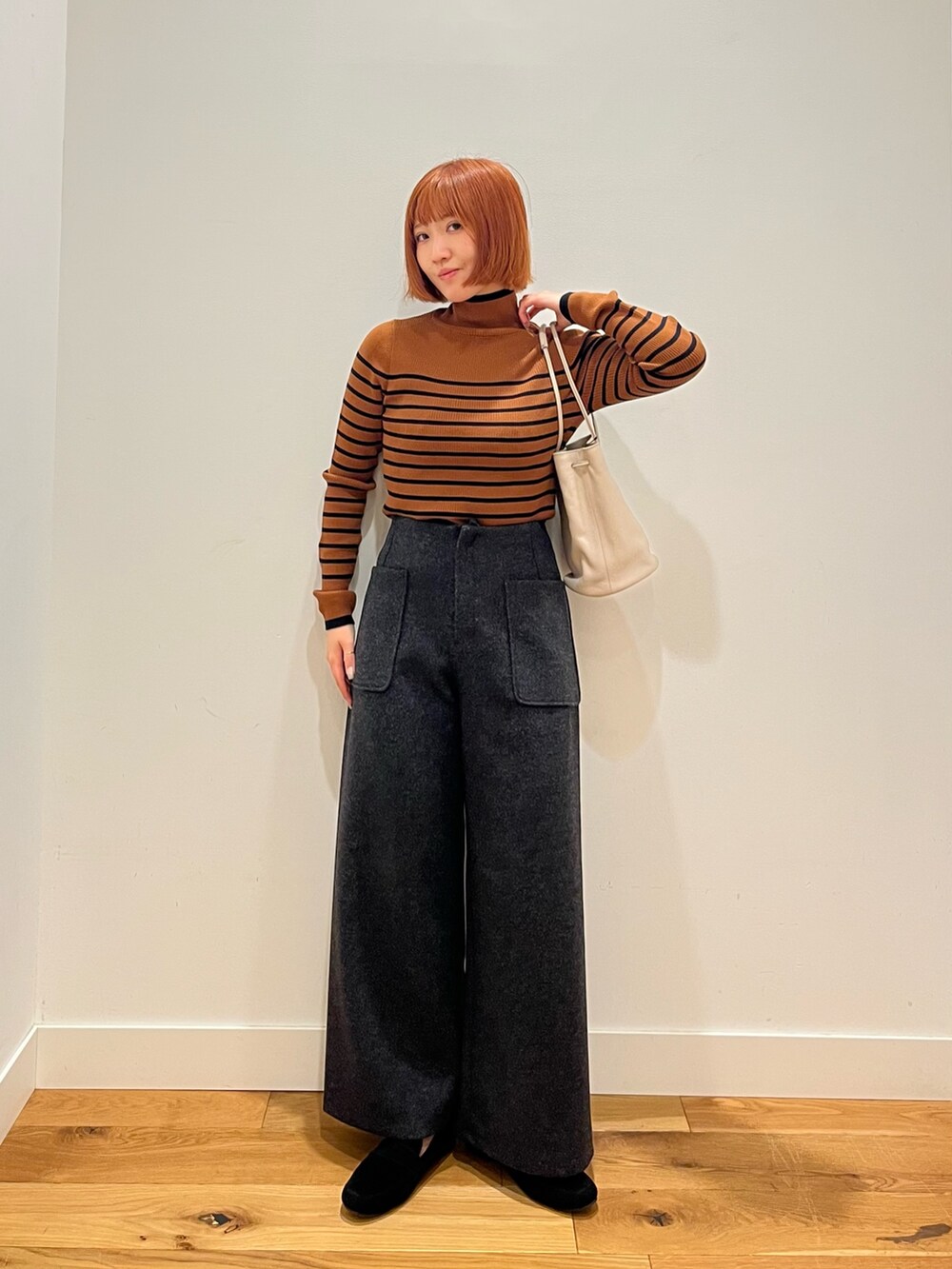 ブラウン系のニット/セーター、グレー系のその他パンツ、グレー系のショルダーバッグを着用したレディースの冬コーディネートの2枚目の写真