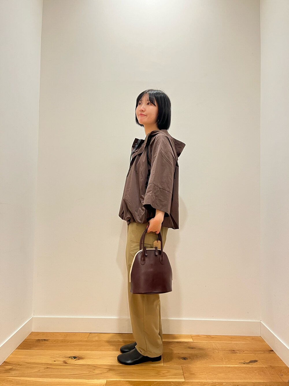 ブラウン系のその他アウター、ベージュ系のその他パンツ、レッド系のハンドバッグを着用したレディースの秋コーディネートの2枚目の写真