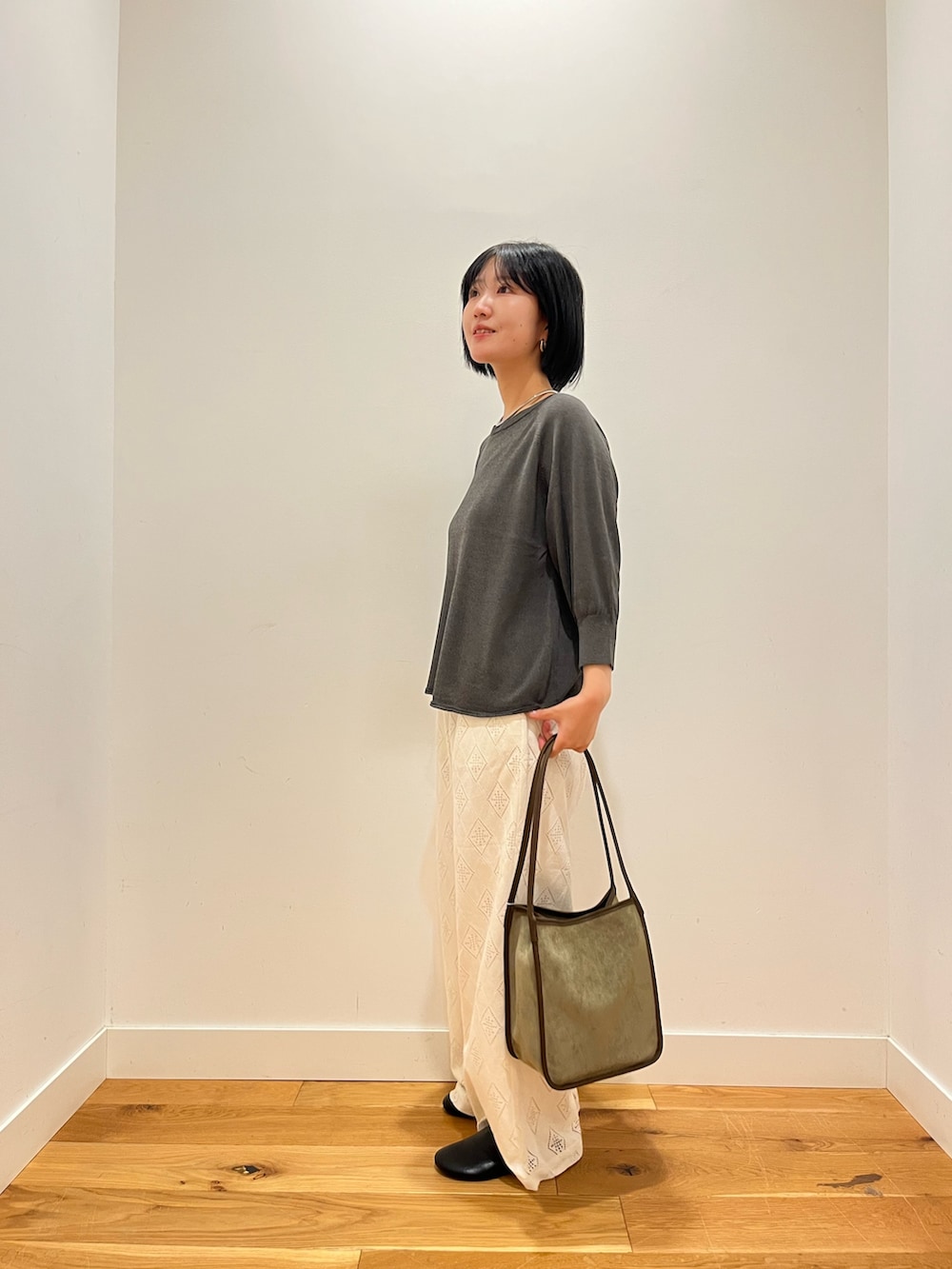 グレー系のニット/セーター、ホワイト系のその他パンツ、グリーン系のトートバッグを着用したレディースの秋コーディネートの2枚目の写真