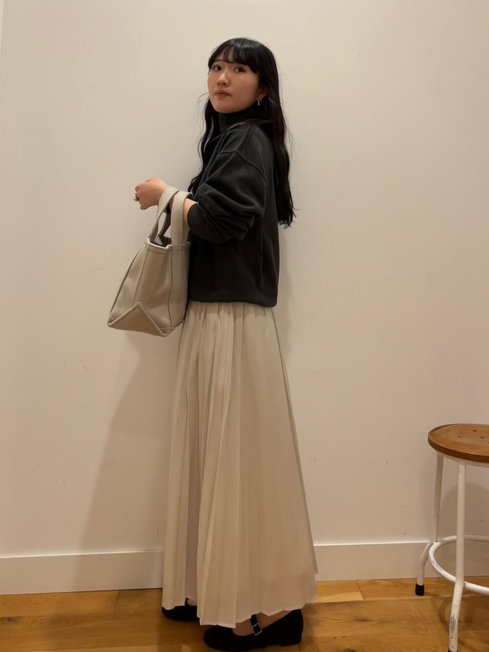 ブラック系のスウェット、ブラウン系のスカート、ベージュ系のトートバッグを着用したレディースの秋コーディネートの2枚目の写真
