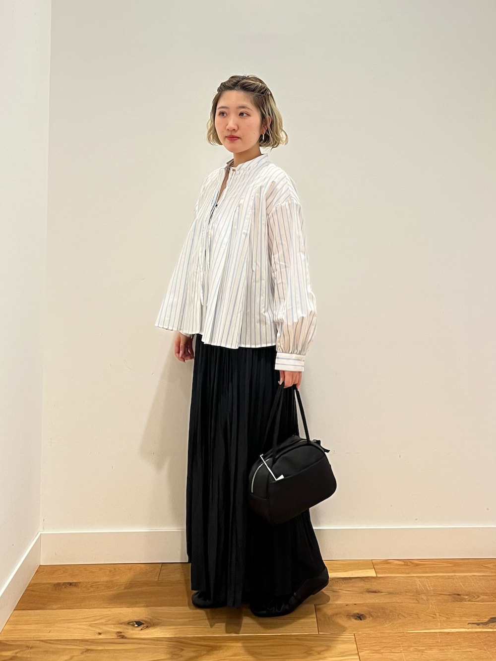 ブラック系のスカート、ホワイト系のシャツ/ブラウスを着用したレディースの春コーディネートの2枚目の写真