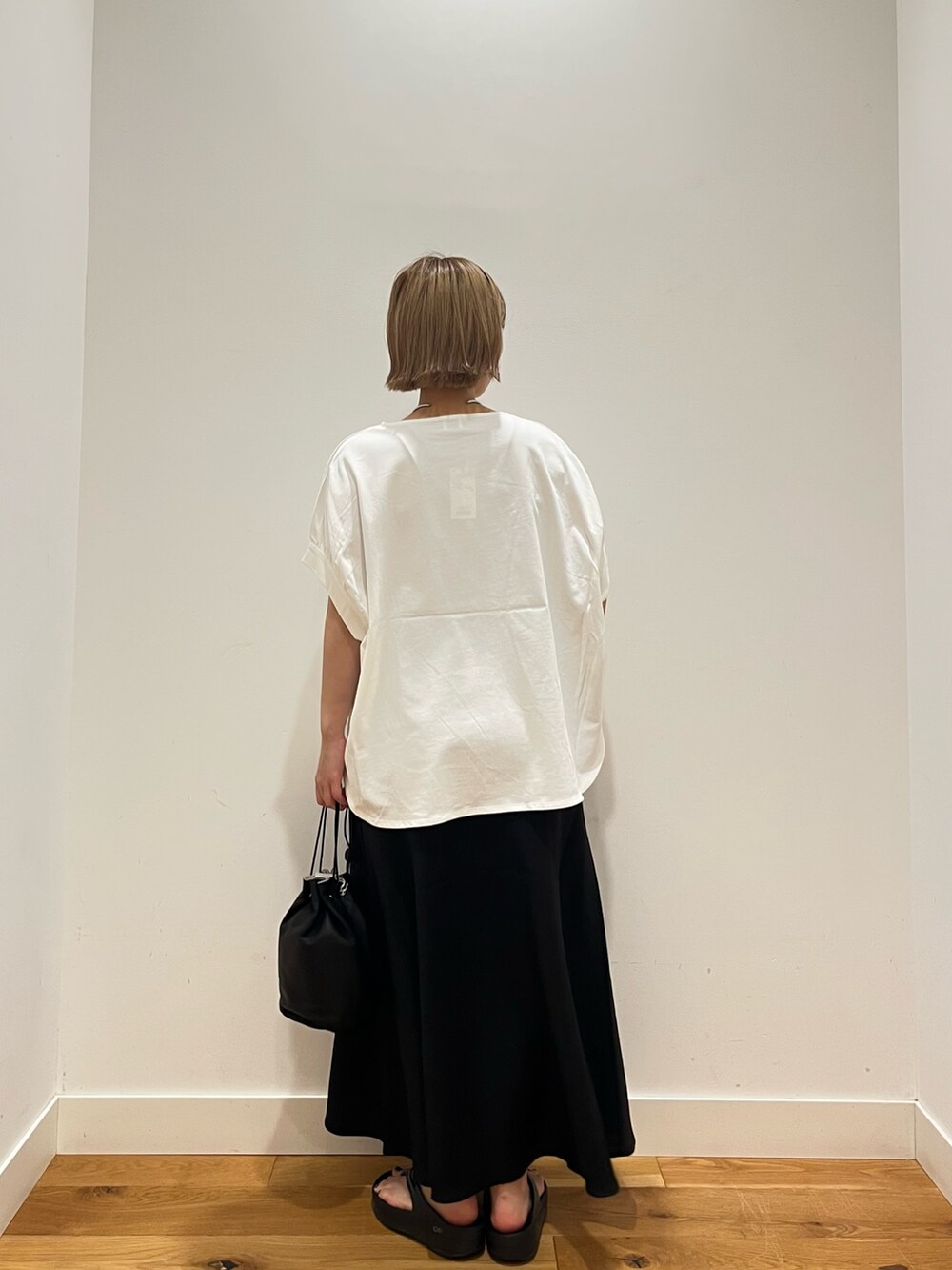 ブラック系のスカート、ホワイト系のTシャツ/カットソー、ブラック系のショルダーバッグを着用したレディースの夏コーディネートの3枚目の写真