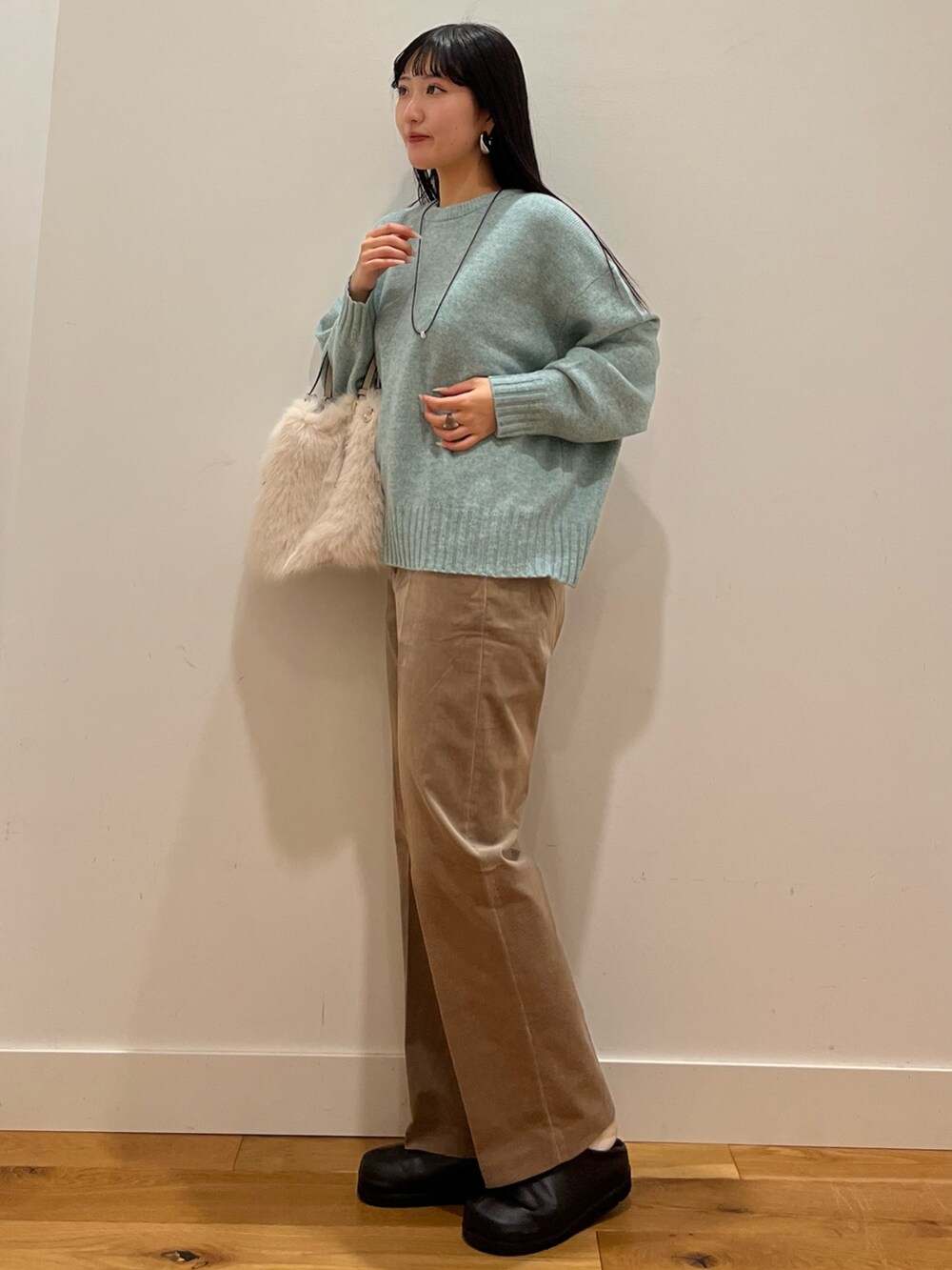 グリーン系のニット/セーター、ベージュ系のその他パンツ、シルバー系のネックレスを着用したレディースの秋コーディネートの2枚目の写真