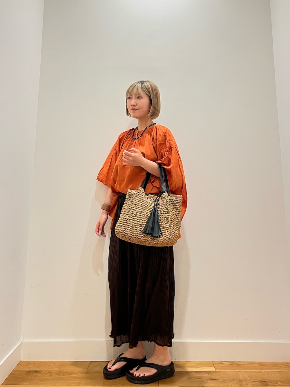 ブラウン系のスカート、オレンジ系のシャツ/ブラウス、ブルー系のネックレスを着用したレディースの夏コーディネートの2枚目の写真
