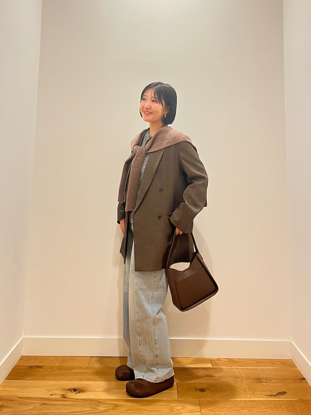 ブルー系のデニムパンツ、ブラウン系のその他アウター、ブルー系のTシャツ/カットソーを着用したレディースの秋コーディネートの2枚目の写真
