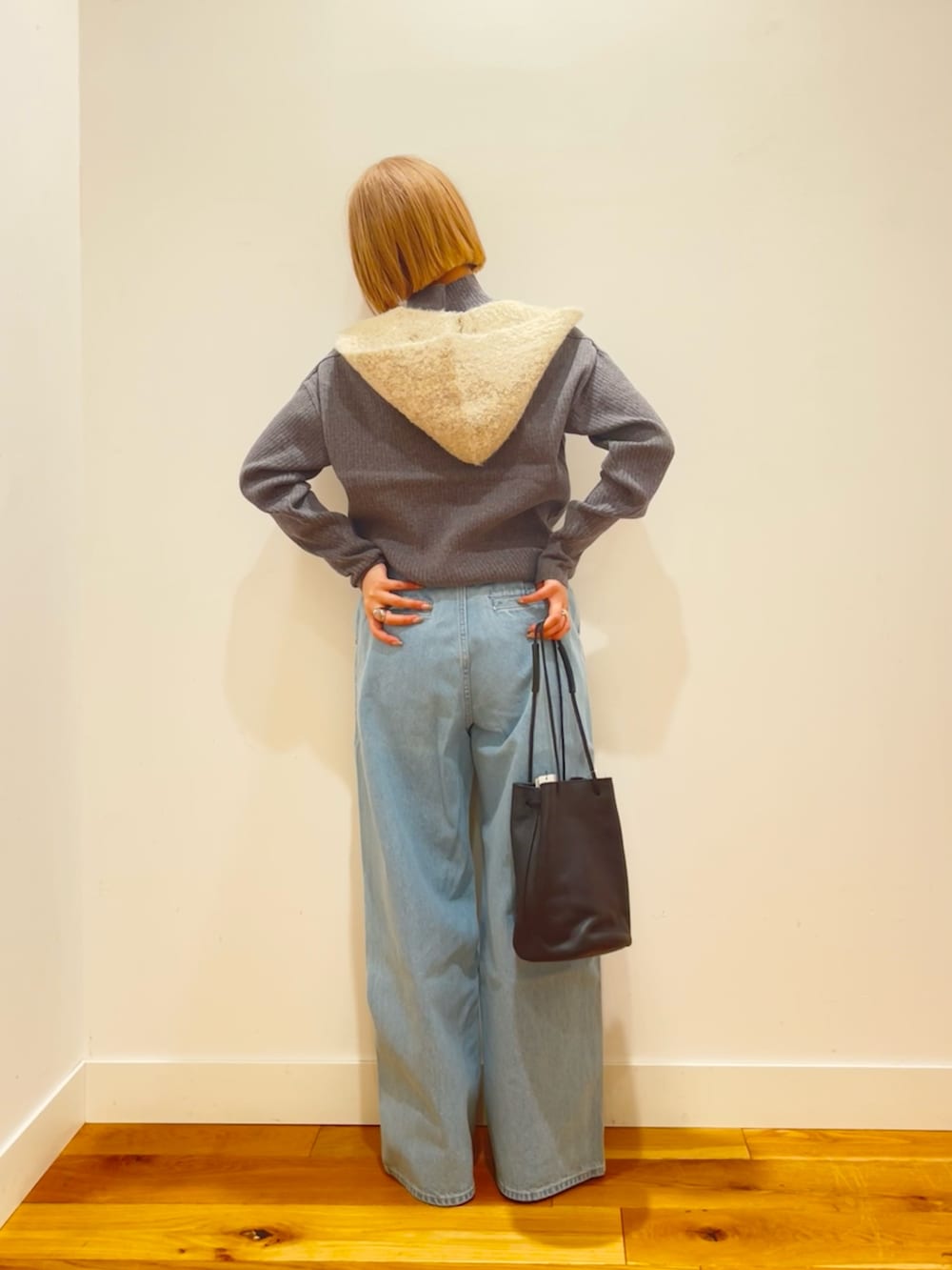 グレー系のニット/セーター、ブルー系のデニムパンツ、ブラック系のショルダーバッグを着用したレディースの冬コーディネートの3枚目の写真