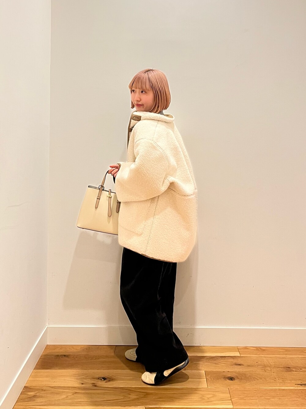 ホワイト系のムートンコート、ベージュ系のスニーカーを着用したレディースの冬コーディネートの3枚目の写真