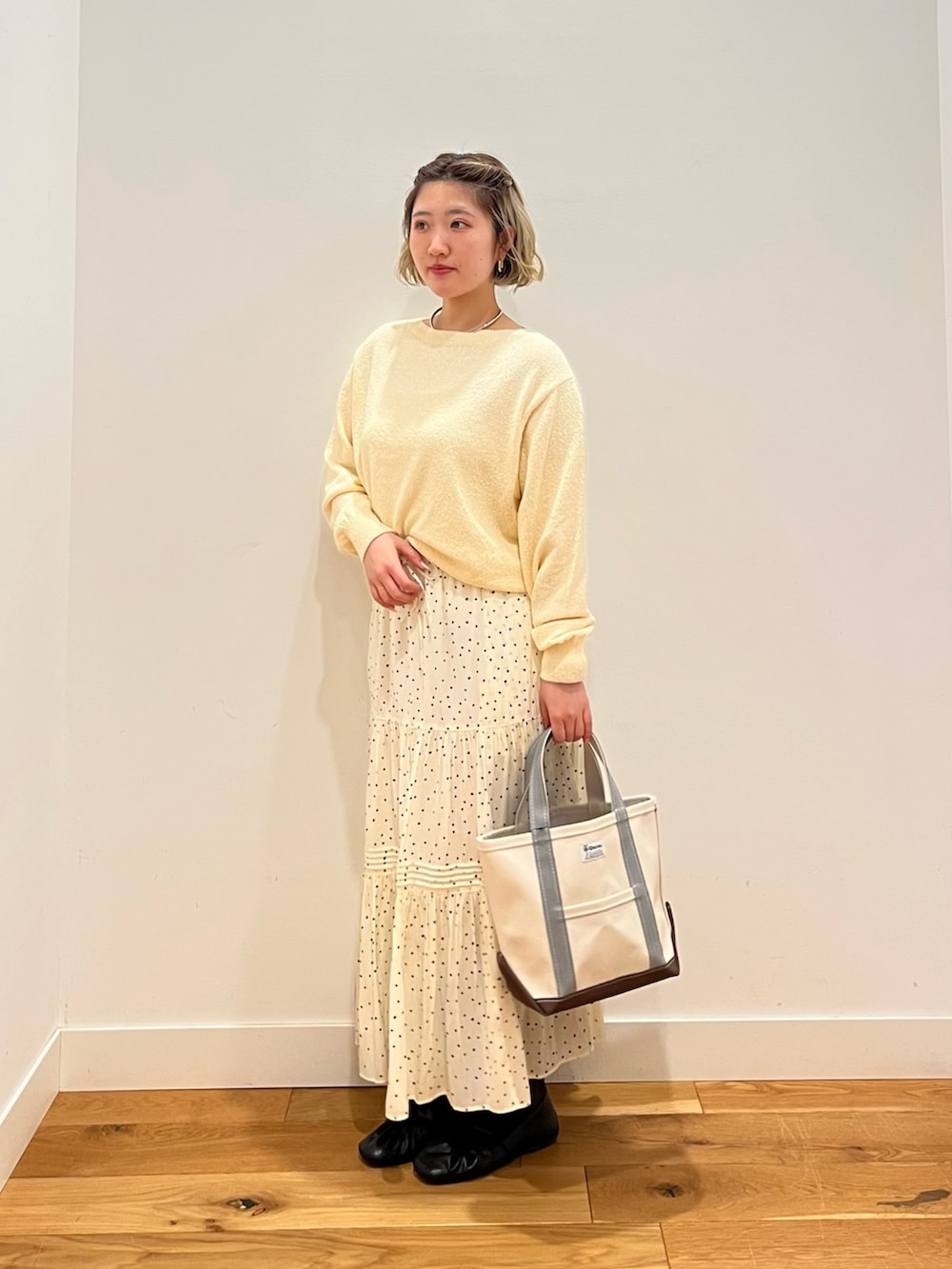 ホワイト系のスカート、ベージュ系のニット/セーターを着用したレディースの春コーディネートの2枚目の写真