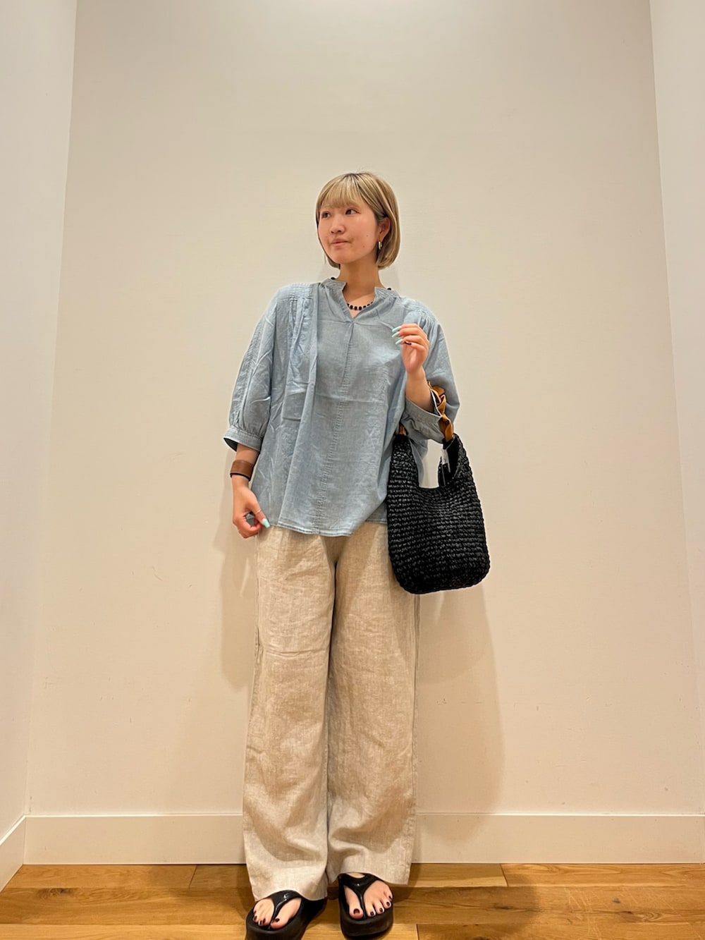 ベージュ系のその他パンツ、ブルー系のシャツ/ブラウス、オレンジ系のかごバッグを着用したレディースの夏コーディネートの2枚目の写真
