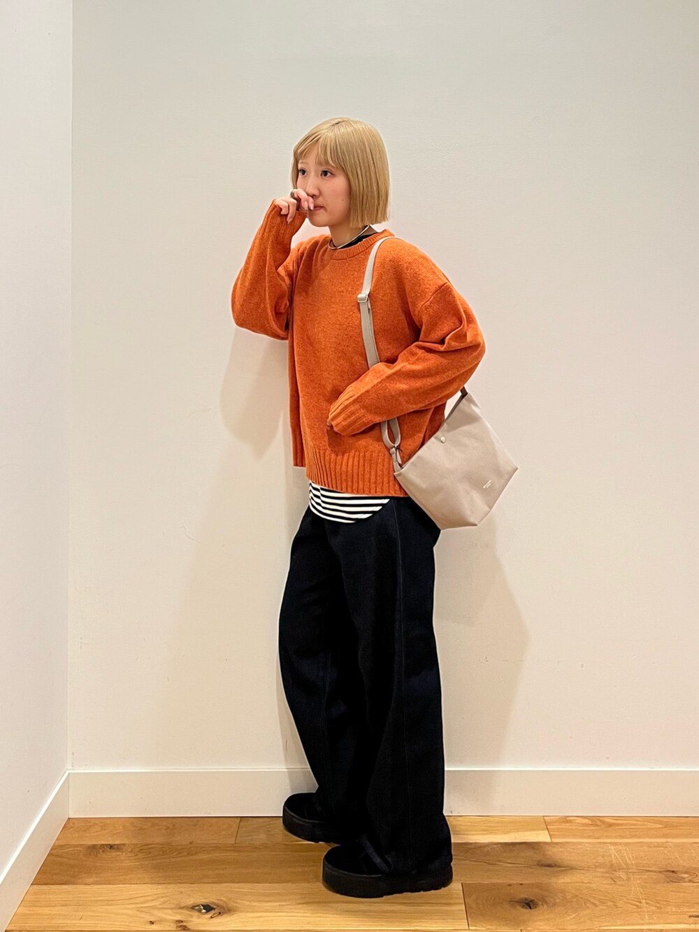 オレンジ系のニット/セーター、ブルー系のデニムパンツ、ホワイト系のTシャツ/カットソーを着用したレディースの冬コーディネートの2枚目の写真