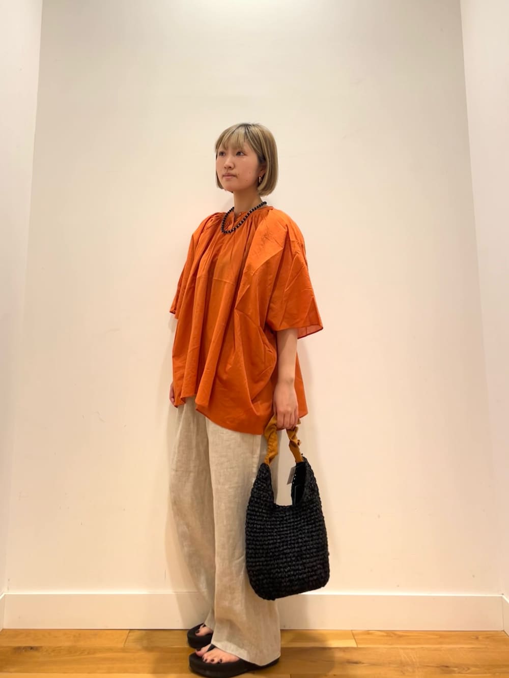 オレンジ系のシャツ/ブラウス、ベージュ系のその他パンツ、オレンジ系のかごバッグを着用したレディースの夏コーディネートの2枚目の写真