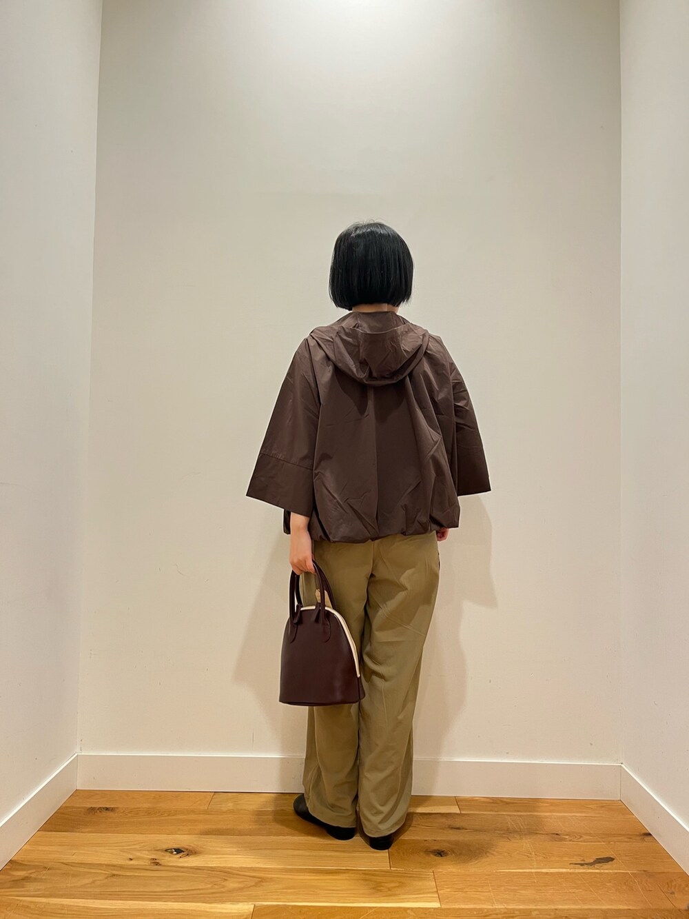 ブラウン系のその他アウター、ベージュ系のその他パンツ、レッド系のハンドバッグを着用したレディースの秋コーディネートの3枚目の写真
