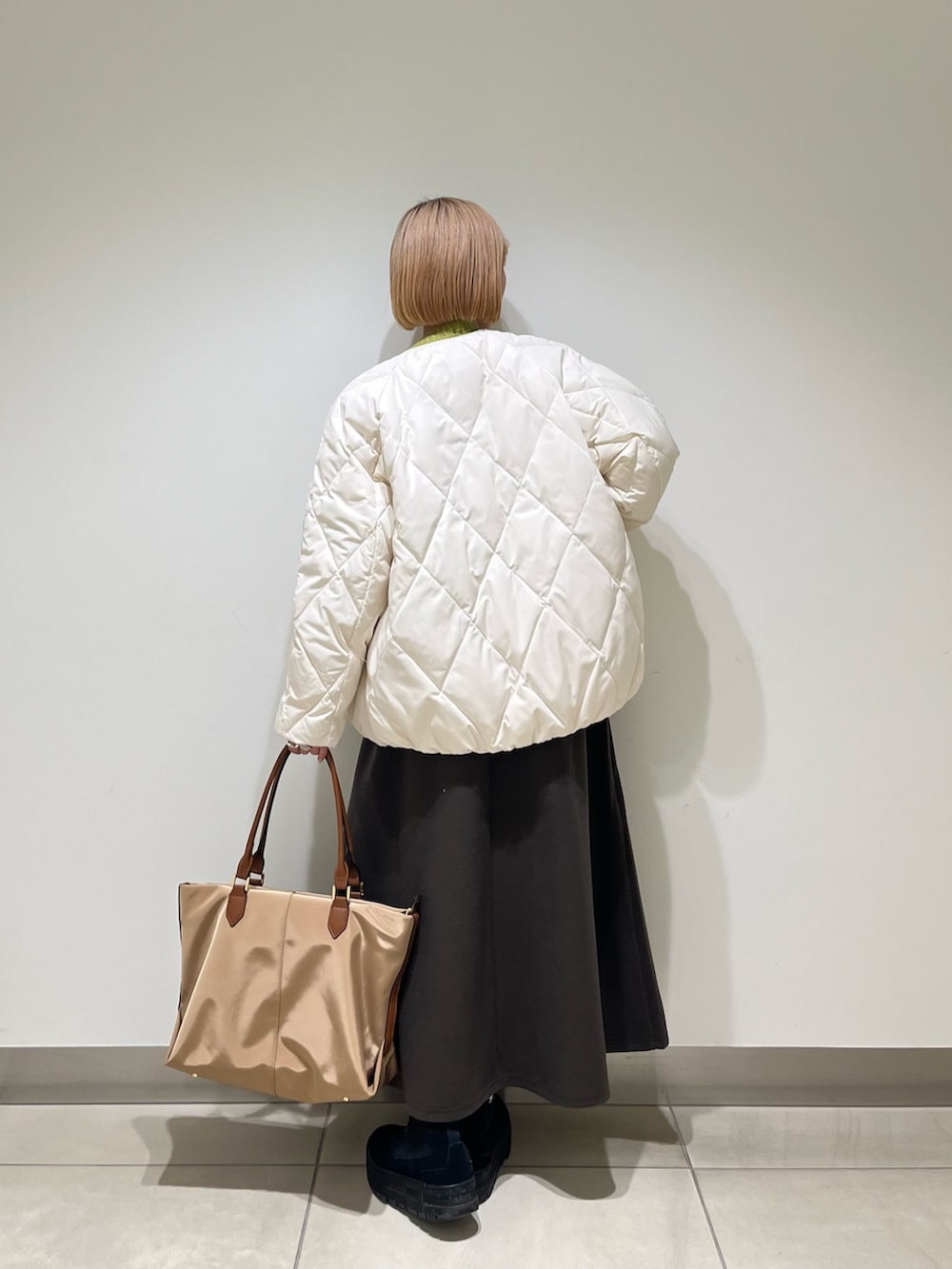 ブラウン系のスカート、ホワイト系のダウンジャケット/コート、グリーン系のニット/セーターを着用したレディースの冬コーディネートの3枚目の写真