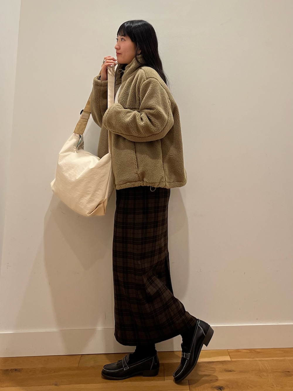 ホワイト系のショルダーバッグ、ベージュ系のブルゾン、ホワイト系のニット/セーターを着用したレディースの秋コーディネートの2枚目の写真