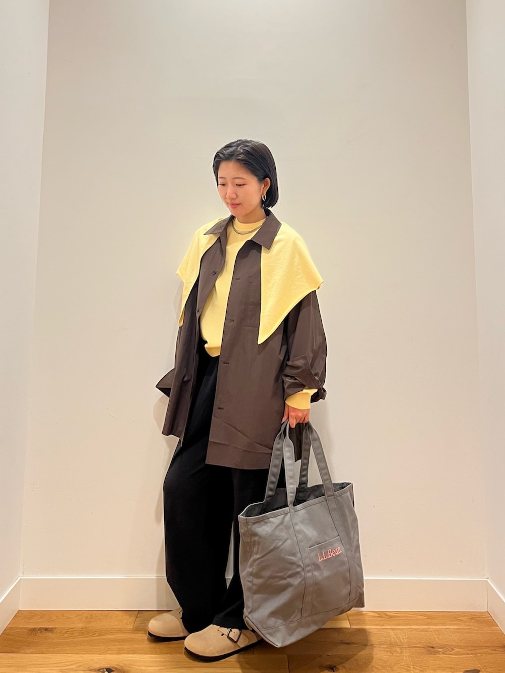 イエロー系のニット/セーター、グレー系のシャツ/ブラウス、グレー系のトートバッグを着用したレディースの秋コーディネートの4枚目の写真
