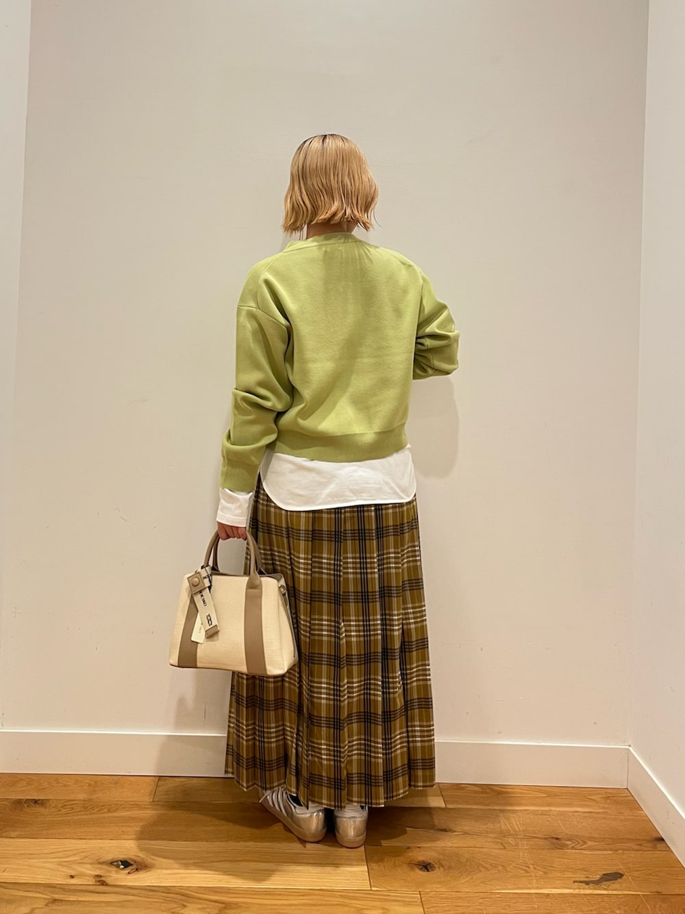 イエロー系のスカート、ホワイト系のTシャツ/カットソー、グリーン系のカーディガン/ボレロを着用したレディースの冬コーディネートの3枚目の写真