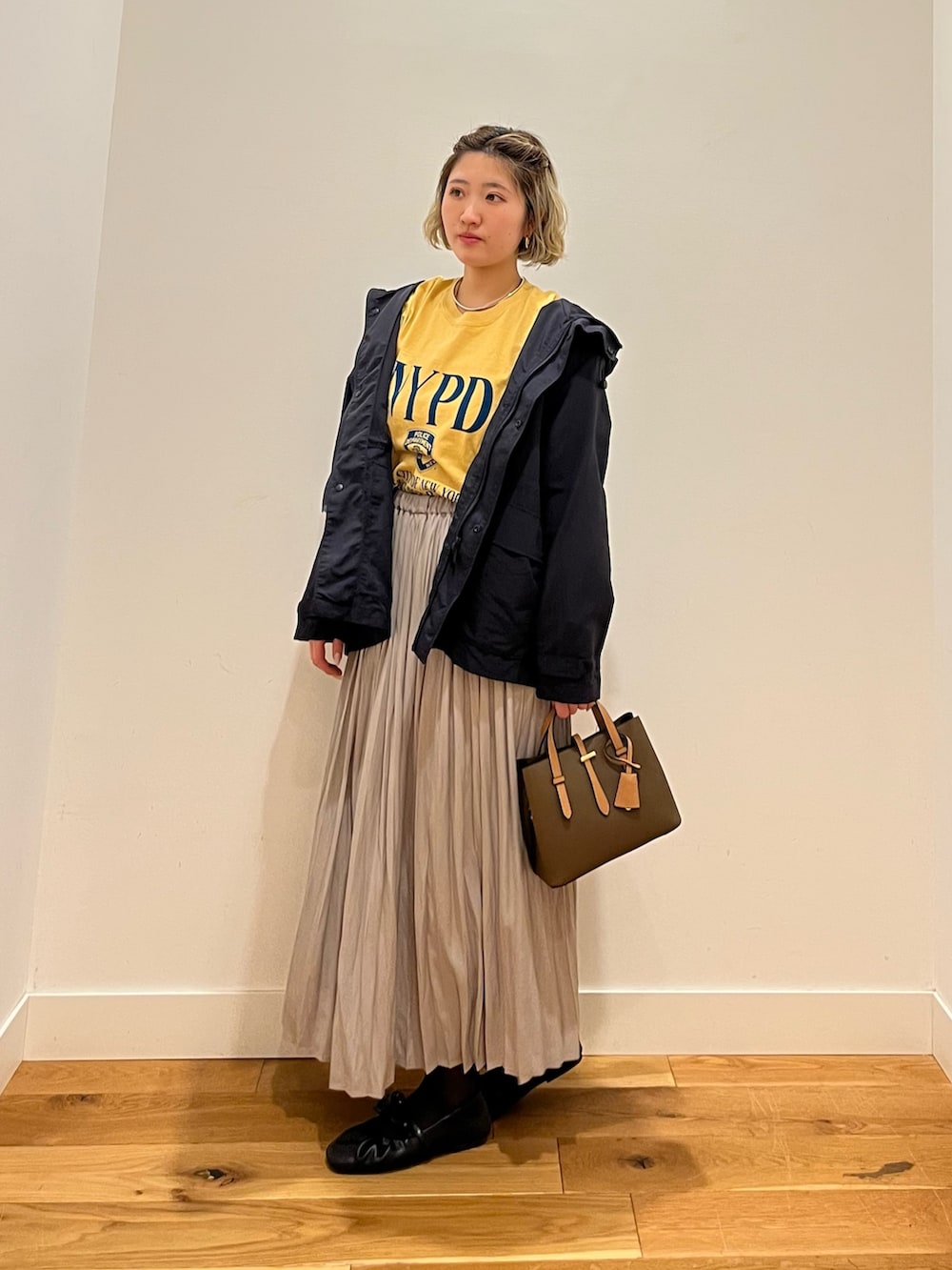 イエロー系のTシャツ/カットソー、ブルー系のマウンテンパーカー、ベージュ系のスカートを着用したレディースの春コーディネートの2枚目の写真