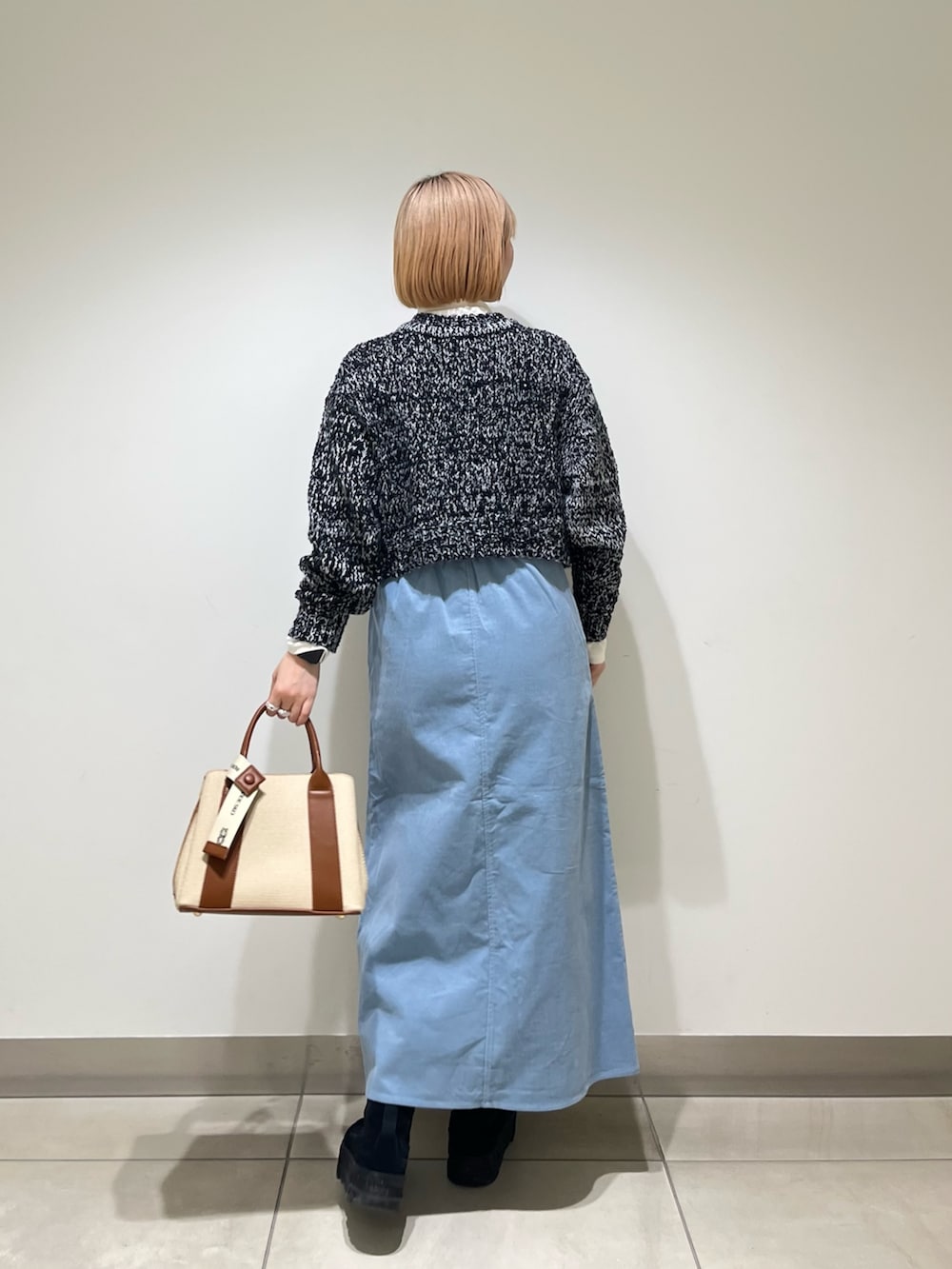 ホワイト系のTシャツ/カットソー、ブラック系のニット/セーター、ブルー系のスカートを着用したレディースの冬コーディネートの3枚目の写真