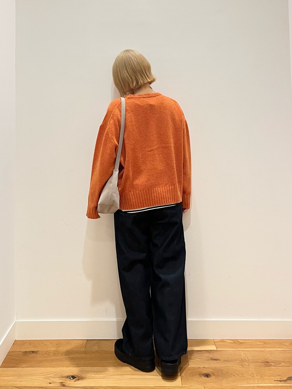 オレンジ系のニット/セーター、ブルー系のデニムパンツ、ホワイト系のTシャツ/カットソーを着用したレディースの冬コーディネートの3枚目の写真