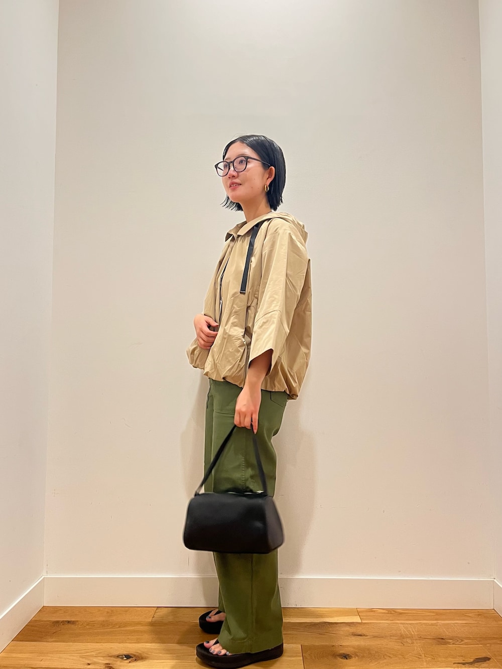 ベージュ系のその他アウター、グリーン系のその他パンツ、ブラック系のハンドバッグを着用したレディースの秋コーディネートの2枚目の写真