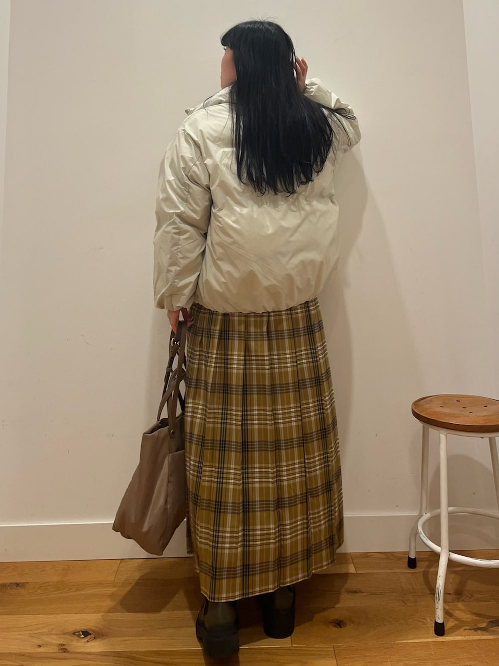 ホワイト系のダウンジャケット/コート、イエロー系のスカート、ベージュ系のバッグを着用したレディースの秋コーディネートの3枚目の写真