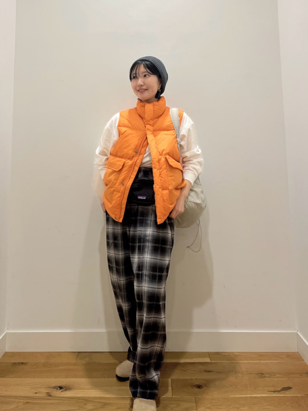 オレンジ系のダウンベスト、ホワイト系のTシャツ/カットソー、グレー系のバックパック/リュックを着用したレディースの秋コーディネートの2枚目の写真