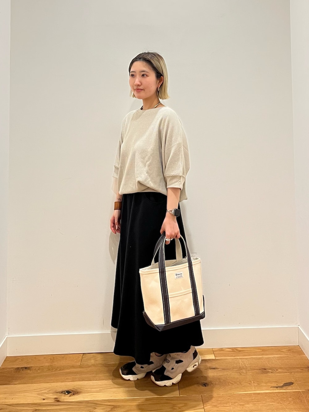 ベージュ系のTシャツ/カットソー、ブラック系のスカートを着用したレディースの春コーディネートの2枚目の写真