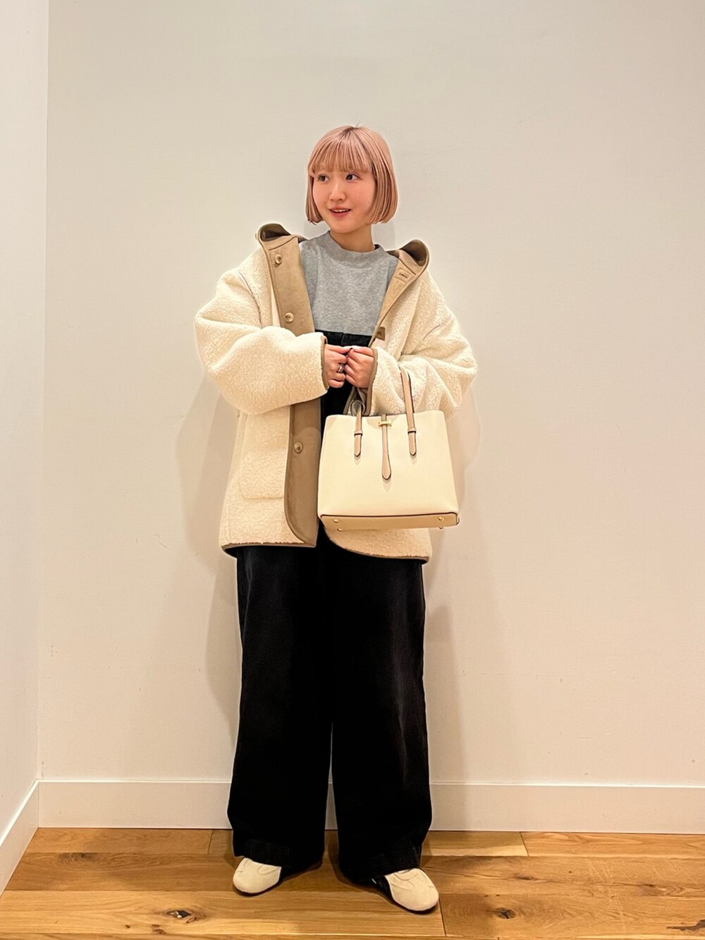 ホワイト系のムートンコート、ベージュ系のスニーカーを着用したレディースの冬コーディネートの2枚目の写真