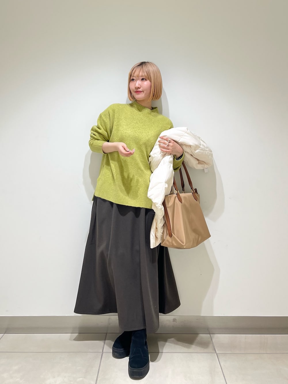 ブラウン系のスカート、ホワイト系のダウンジャケット/コート、グリーン系のニット/セーターを着用したレディースの冬コーディネートの4枚目の写真