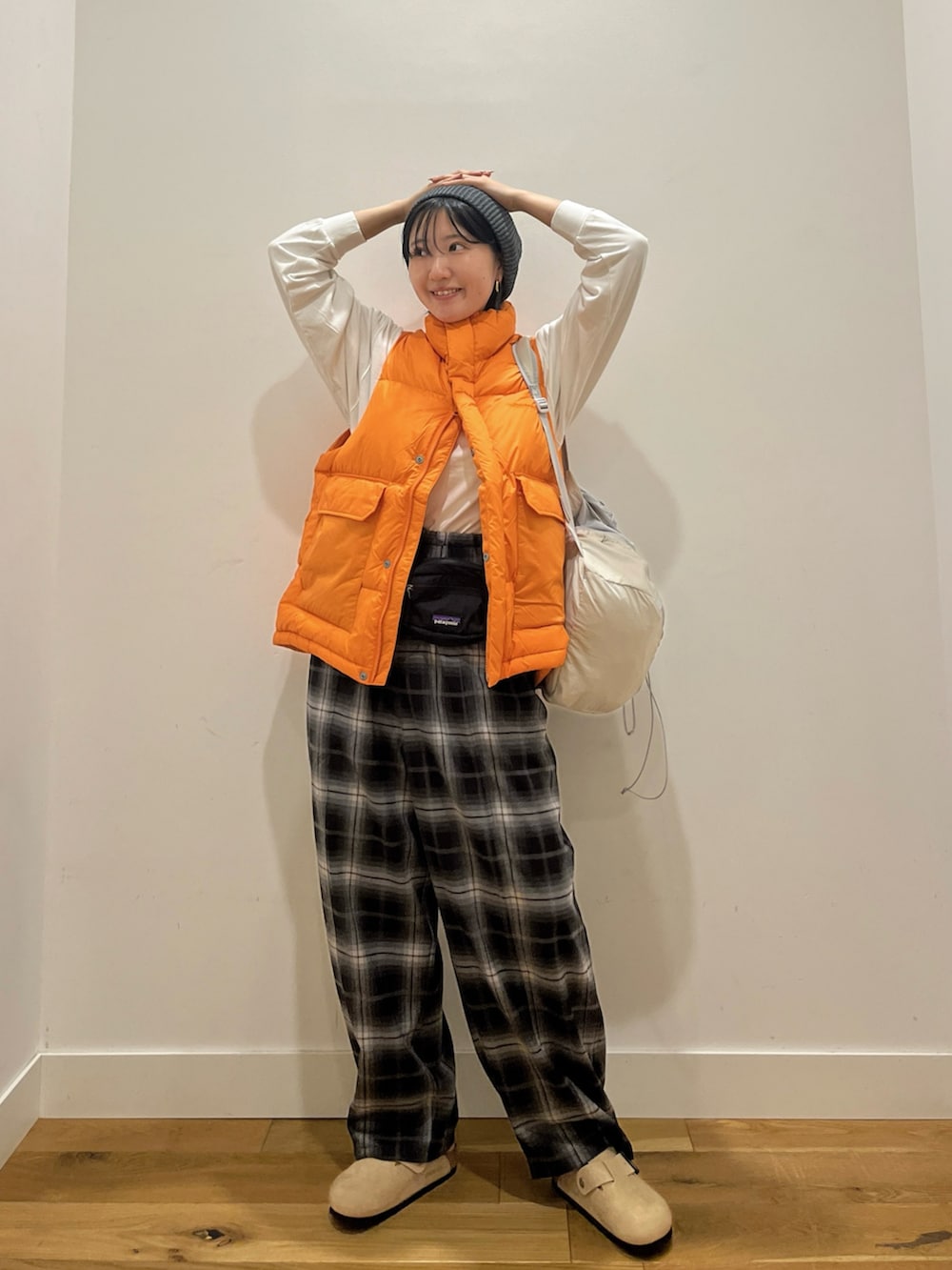オレンジ系のダウンベスト、ホワイト系のTシャツ/カットソー、グレー系のバックパック/リュックを着用したレディースの秋コーディネートの5枚目の写真