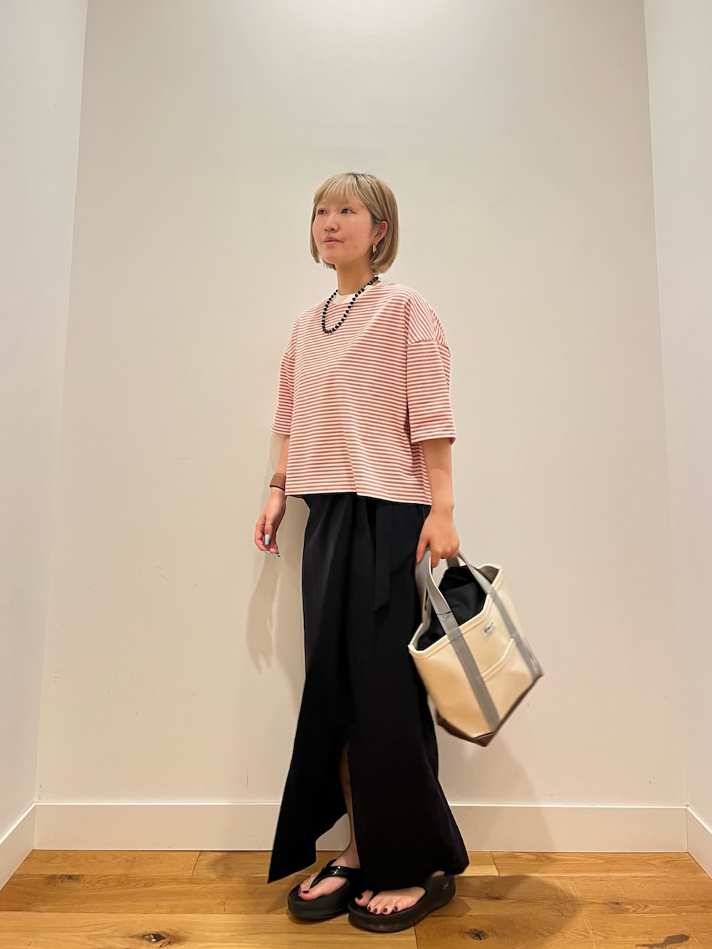 ブラック系のスカート、レッド系のTシャツ/カットソー、グリーン系のトートバッグを着用したレディースの夏コーディネートの2枚目の写真