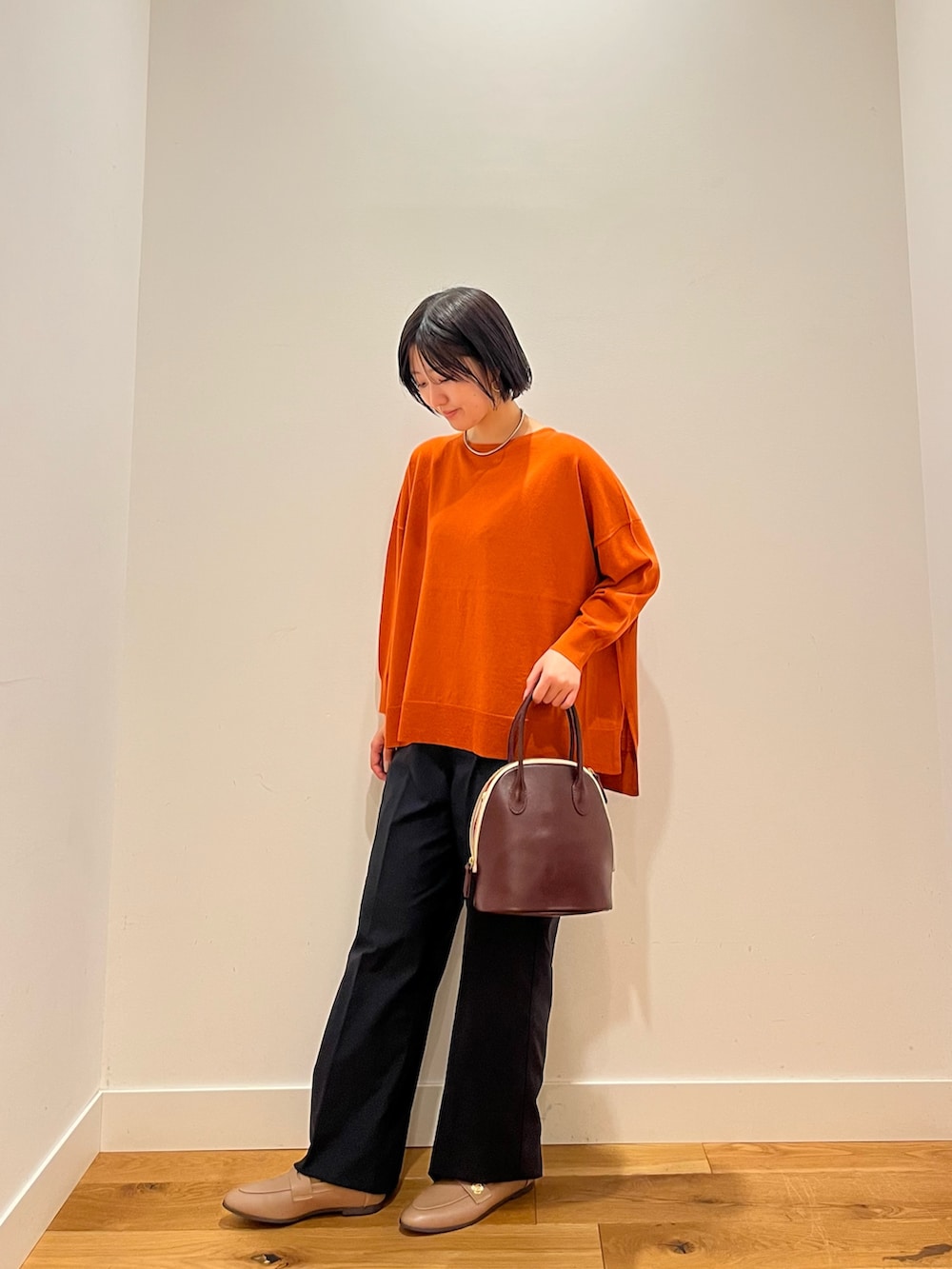 オレンジ系のニット/セーター、グレー系のその他パンツを着用したレディースの秋コーディネートの3枚目の写真