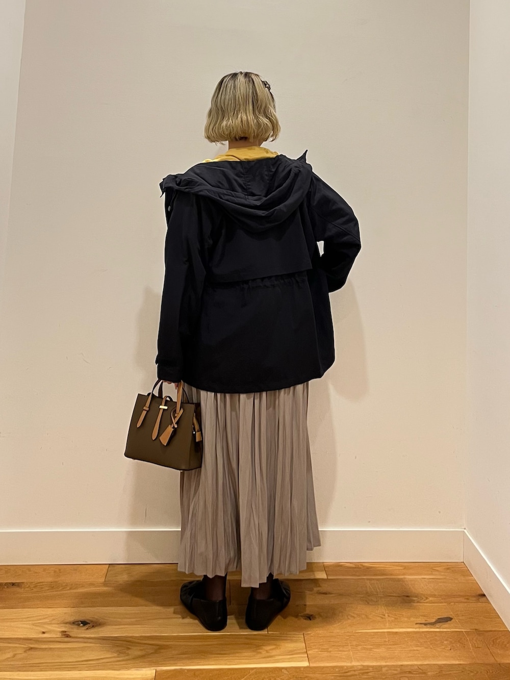 イエロー系のTシャツ/カットソー、ブルー系のマウンテンパーカー、ベージュ系のスカートを着用したレディースの春コーディネートの3枚目の写真