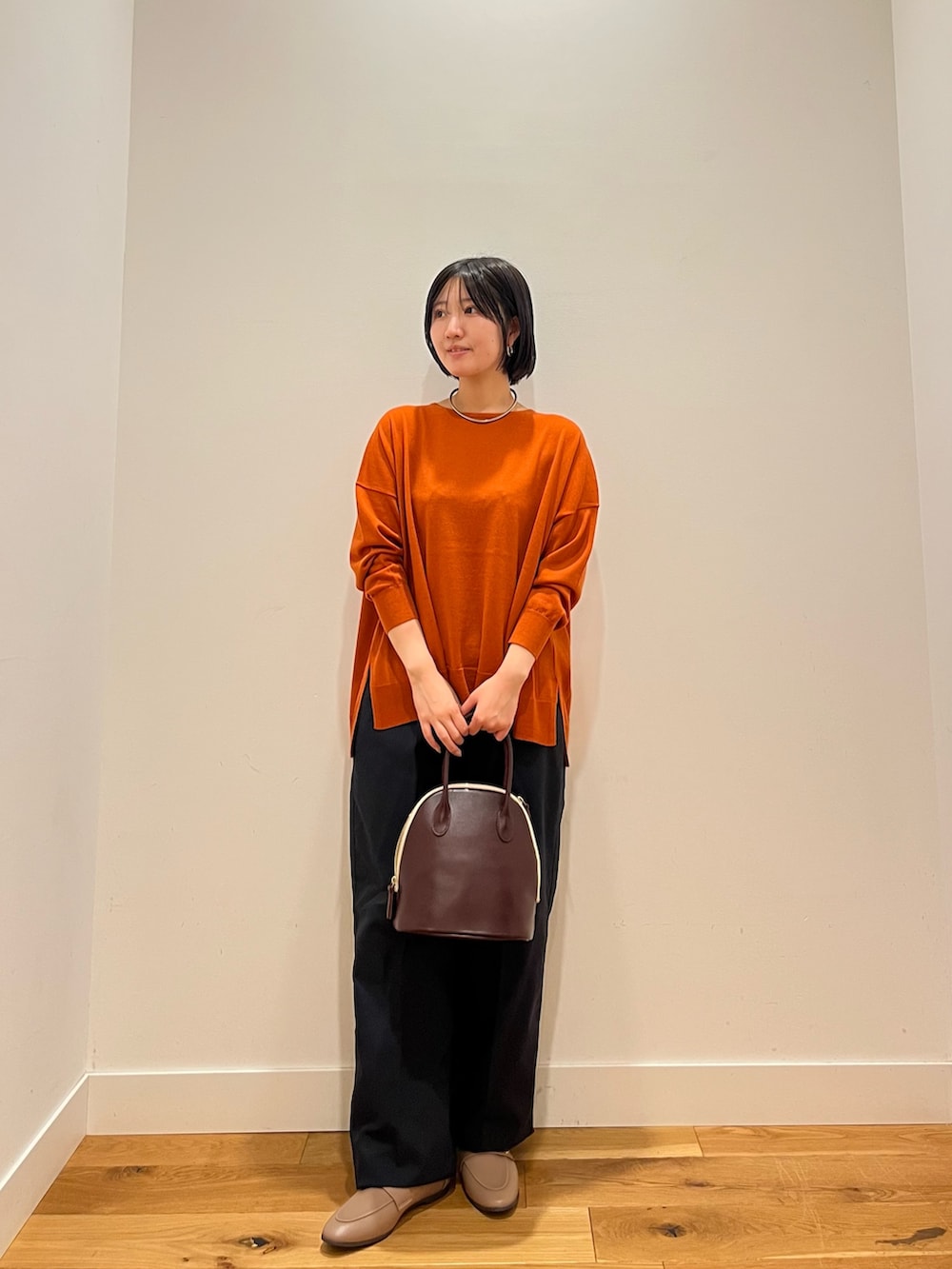 オレンジ系のニット/セーター、グレー系のその他パンツを着用したレディースの秋コーディネートの2枚目の写真