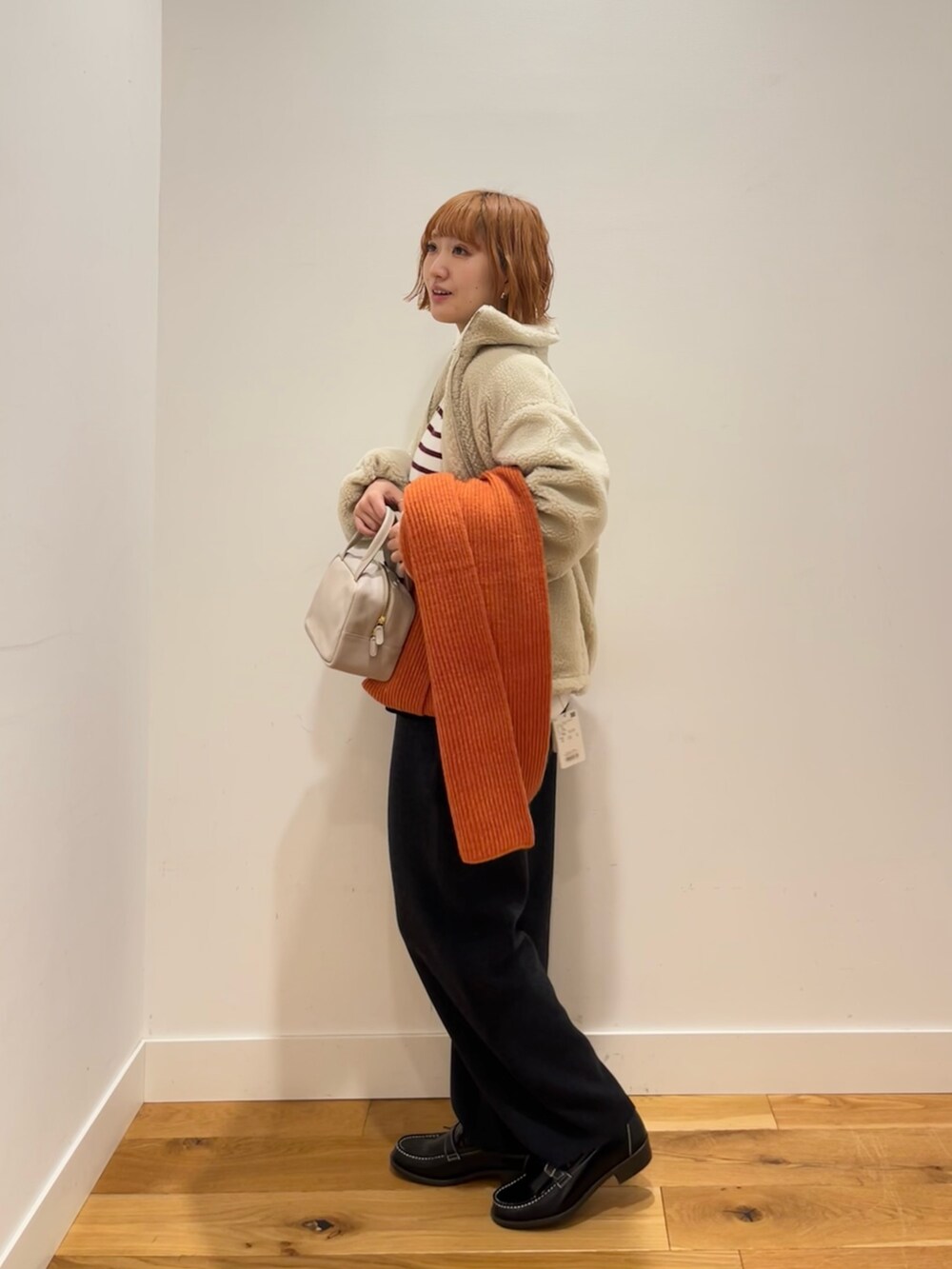 グレー系のボストンバッグ、レッド系のニット/セーター、ホワイト系のその他アウターを着用したレディースの冬コーディネートの2枚目の写真