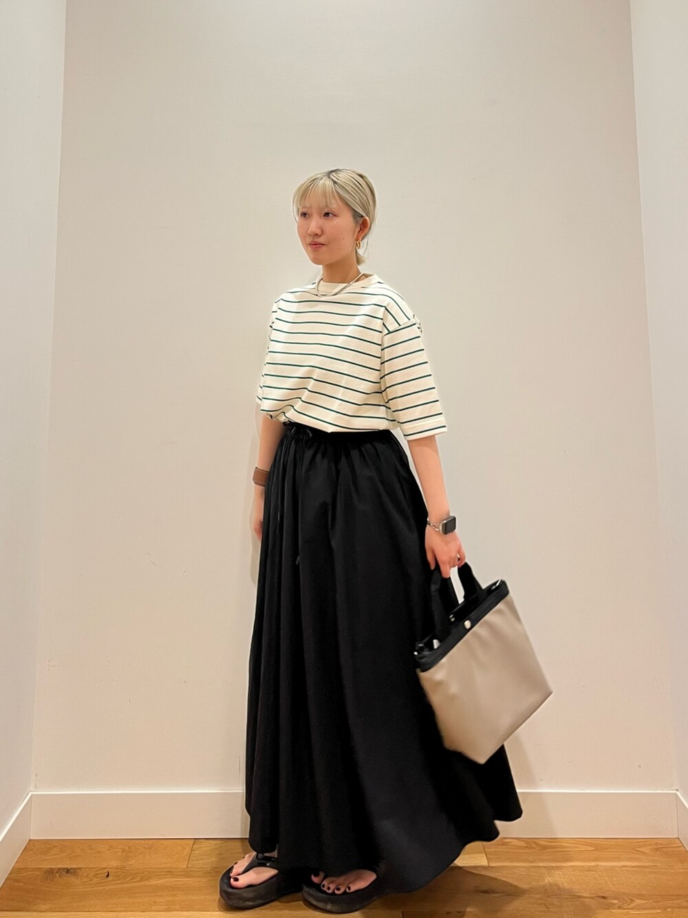 ベージュ系のTシャツ/カットソー、ブラック系のスカートを着用したレディースの春コーディネートの2枚目の写真