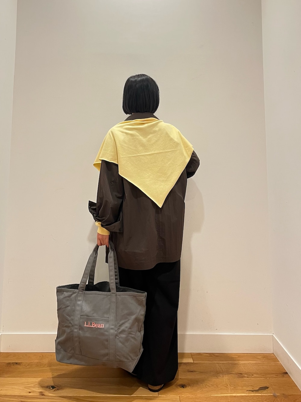 イエロー系のニット/セーター、グレー系のシャツ/ブラウス、グレー系のトートバッグを着用したレディースの秋コーディネートの5枚目の写真
