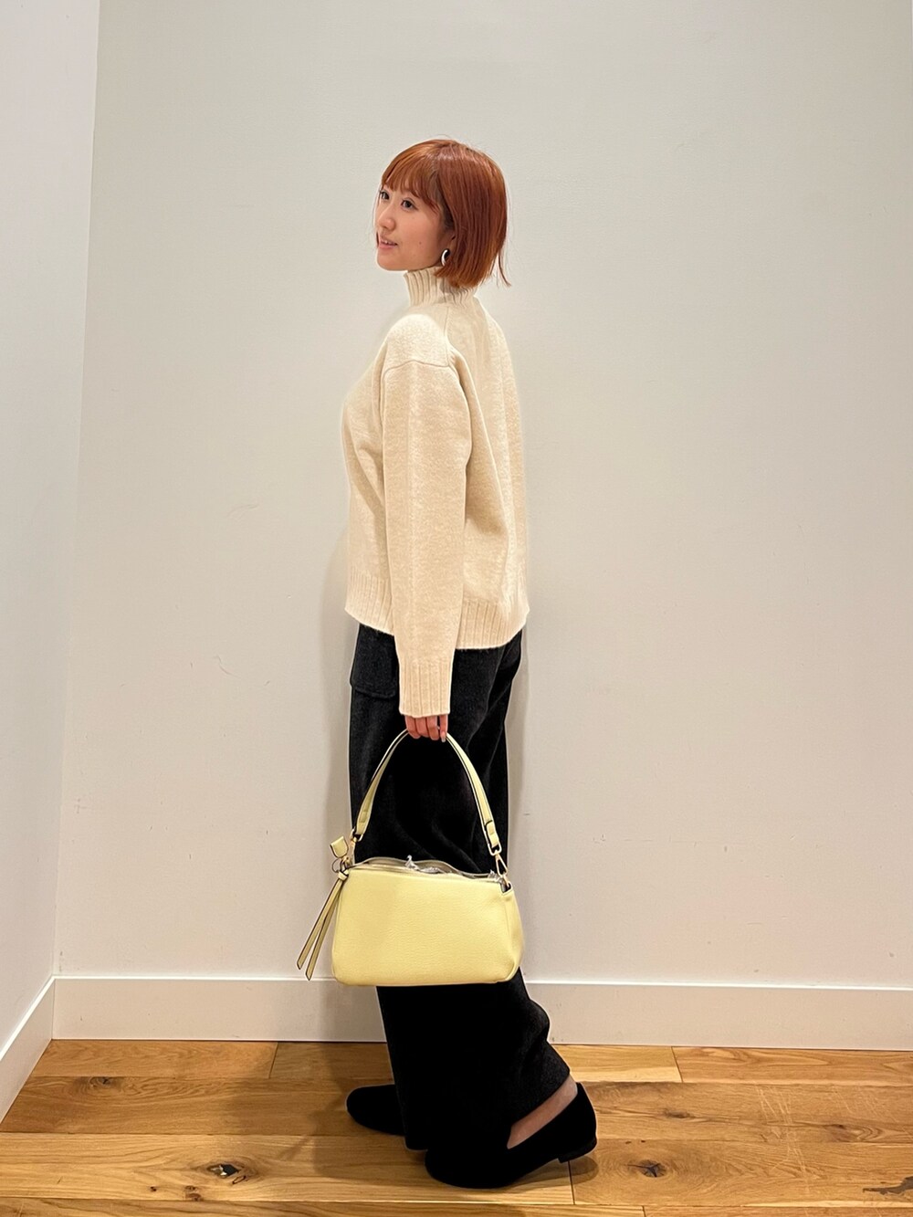 ホワイト系のニット/セーター、イエロー系のバッグ、グレー系のその他パンツを着用したレディースの冬コーディネートの2枚目の写真